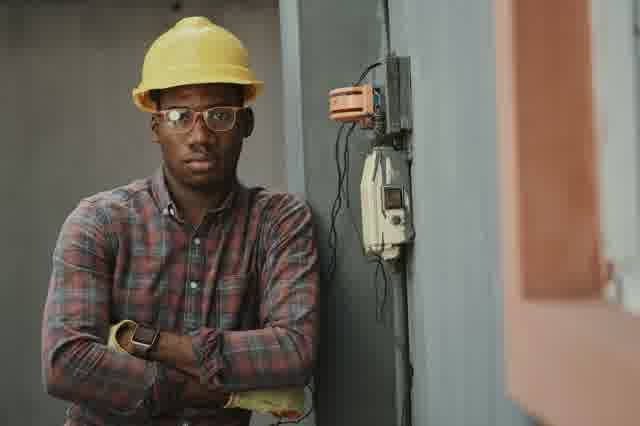 A tradesperson in a hard hat using a power tool.